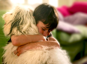 Young Boy Hugging White Dog
